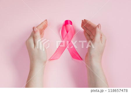 Breast Cancer Awareness Month. Woman's hand holds pink ribbon. Health care concept, cancer control symbol. Copy space. Breast Cancer Awareness Month. Woman's hand holds pink ribbon. Health care concept, cancer control symbol. Copy space. 118657478