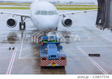Airplane is rolled out of terminal gate in preparation for departure during rain Airplane is rolled out of terminal gate in preparation for departure during rain 118657556
