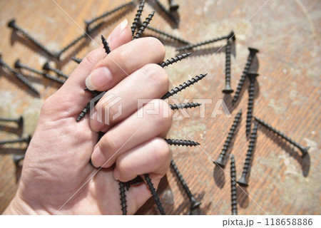selective focus at the female hand, holding screws, concept of tight 118658886