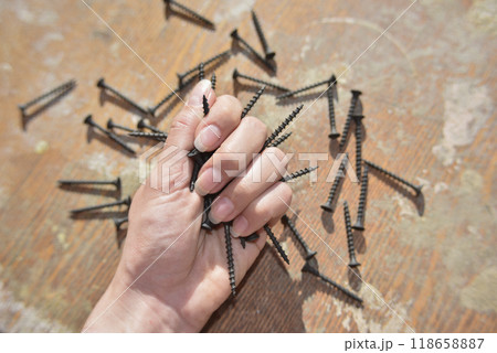 selective focus at the female hand, holding screws, concept of tight and strong 118658887
