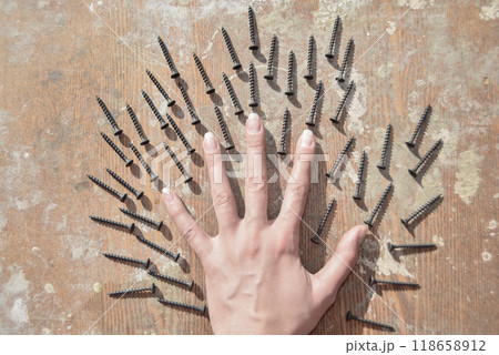 the hand surronded ith screws on the old wooden table the hand surronded ith screws on the old wooden table 118658912