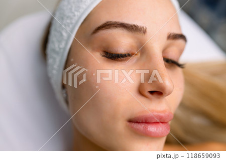 Beautiful relaxed woman at beautician cabinet receiving anti wrinkle injections on cheekbones, lying with closed eyes in beauty salon Beautiful relaxed woman at beautician cabinet receiving anti wrinkle injections on cheekbones, lying with closed eyes in beauty salon 118659093