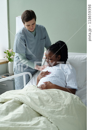Nurse Assisting Pregnant Patient in Hospital Room 118659398