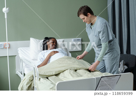 Caring Nurse Assisting Patient in Hospital Room 118659399