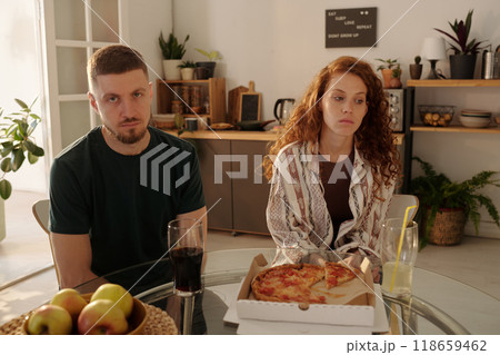 Troubled couple sitting by kitchen table 118659462