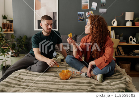 Young couple eating chips on bed 118659502