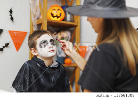 Mother applying Halloween makeup on boy's face 118661309