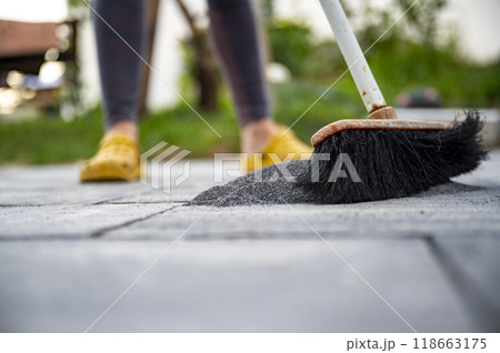 Person brushing filling sand into the gaps between newly layed concrete tiles in a do it yourself project Person brushing filling sand into the gaps between newly layed concrete tiles in a do it yourself project 118663175
