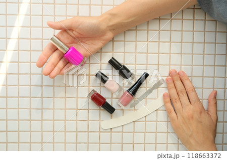 top view of person chooses nail polish for coloring nails. Women's hands manicure tools. top view of person chooses nail polish for coloring nails. Women's hands manicure tools. 118663372