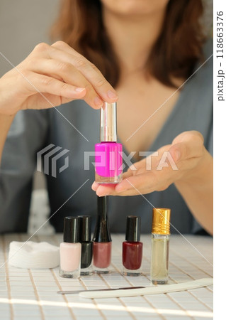 woman gets manicure at home, cuts the cuticle. person chooses nail polish for coloring nails 118663376