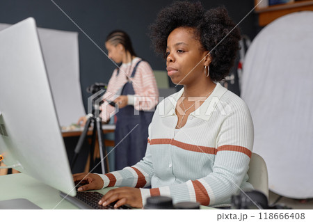 Portrait of African American woman as female photographer using desktop computer in professional photo studio doing selection or retouch Portrait of African American woman as female photographer using desktop computer in professional photo studio doing selection or retouch 118666408