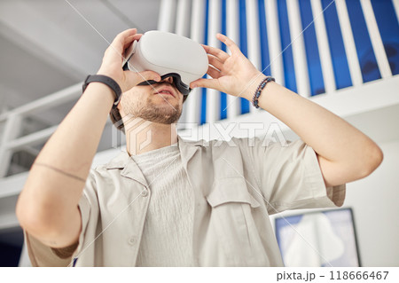 Low angle portrait of man wearing VR headset in modern art museum and looking at digital artwork, copy space 118666467