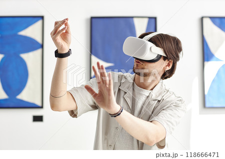 Minimal portrait of man wearing VR headset in modern art museum and while interacting with invisible digital artwork, copy space Minimal portrait of man wearing VR headset in modern art museum and while interacting with invisible digital artwork, copy space 118666471