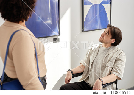 Portrait of young man with disability using wheelchair in art gallery and looking at paintings enjoying accessible art show experience Portrait of young man with disability using wheelchair in art gallery and looking at paintings enjoying accessible art show experience 118666510