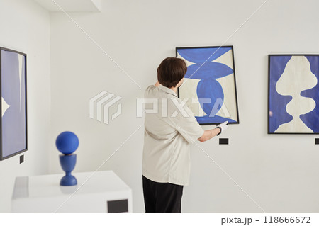 Minimal back view of man hanging abstract art painting on wall while preparing for exhibition in museum copy space Minimal back view of man hanging abstract art painting on wall while preparing for exhibition in museum copy space 118666672