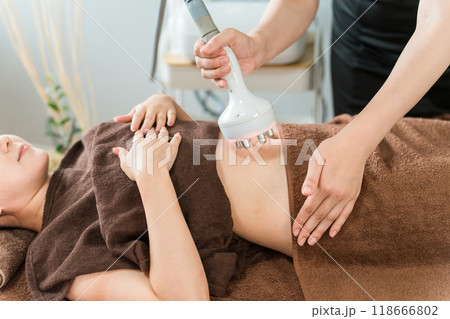 エステサロンでキャビテーション・エステマシンを使って痩身エステを行うエステティシャンと女性 エステサロンでキャビテーション・エステマシンを使って痩身エステを行うエステティシャンと女性 118666802