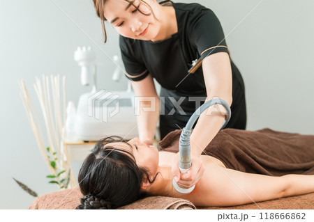 エステサロンでマシンを使うエステティシャン・セラピスト・スタッフと女性 118666862
