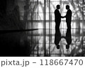 Two businessmen shaking hands in silhouette in office building lobby 118667470