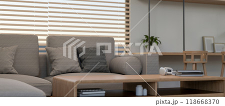 A close-up of a wooden coffee table in a contemporary living room features a comfortable grey sofa. 118668370