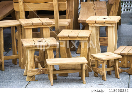 Collection handcrafted wooden stools and benches displayed outdoors showcasing rustic craftsmanship 118668882