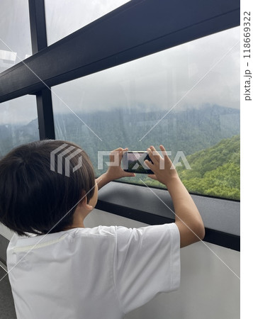 ロープウェイから写真を撮る少年の後ろ姿 118669322