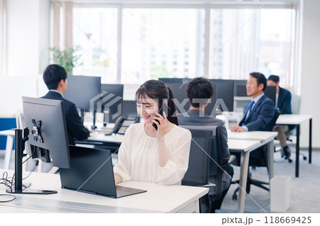 オフィスの中でスマホで通話をするビジネスパーソン 118669425