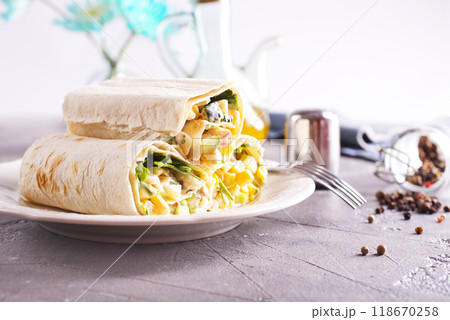 Stuffing, cucumber and corn are added to the unfolded pita bread. Stuffing, cucumber and corn are added to the unfolded pita bread. 118670258