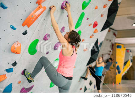 Woman climbing on rock-climbing wall Woman climbing on rock-climbing wall 118670546
