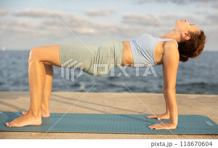 Yoga practice on embankment, female athlete fulfil carry out katuspadapidham 118670604