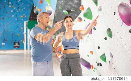 Adult man and young woman posing on climbing wall Adult man and young woman posing on climbing wall 118670654
