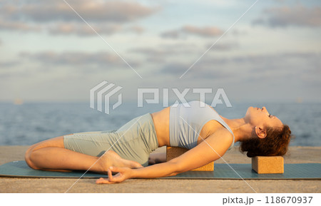 Yoga practice on embankment, female athlete fulfil carry out frog asana with blocks 118670937