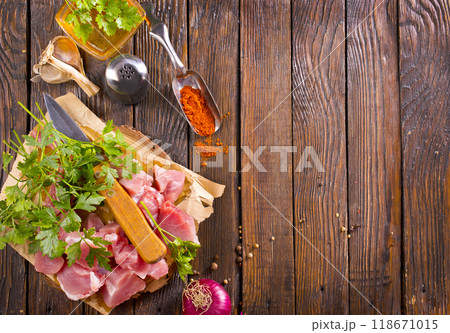 Raw beef meat chopped in cubes with bunch of fresh parsley on wooden cutting board for cooking Raw beef meat chopped in cubes with bunch of fresh parsley on wooden cutting board for cooking 118671015