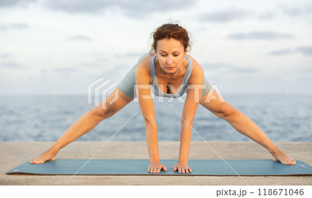 Yoga practice on embankment, female athlete fulfil carry out Prasarita Padottanasana Yoga practice on embankment, female athlete fulfil carry out Prasarita Padottanasana 118671046