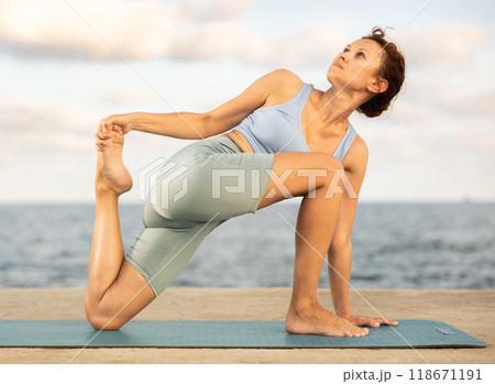 Yoga practice on embankment, female athlete fulfil carry out parivritta Anjaneyasana 118671191