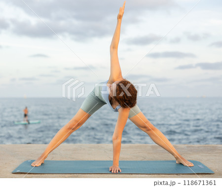 Yoga pose called pyramid performed by a woman on seashore 118671361
