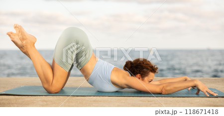Woman in yoga pose on seashore - dog pose Woman in yoga pose on seashore - dog pose 118671418