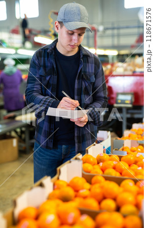Positive male worker fills out a document at a citrus processing plant. 118671576