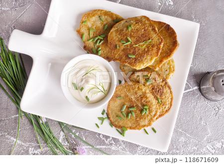 Fried potato pancakes with white sauce on plate 118671609