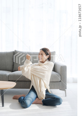 リビングの床に座って伸びをする若い女性 118671657