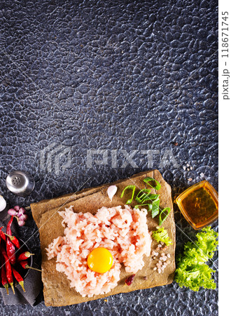 Raw minced meat in bowl on dark table and ingredients. Raw minced meat in bowl on dark table and ingredients. 118671745