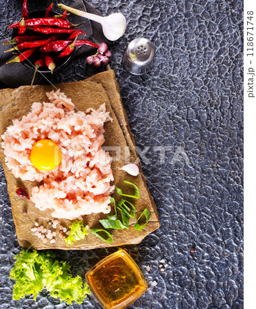 Raw minced meat in bowl on dark table and ingredients. 118671748