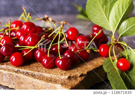 Fresh sour cherries and green leaves on the board. 118671830
