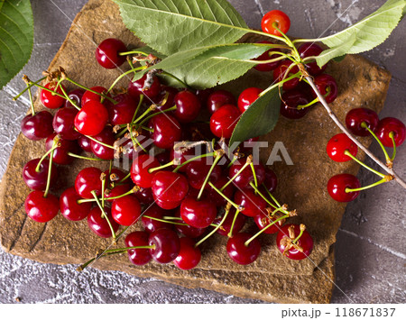 Fresh sour cherries and green leaves on the board. 118671837