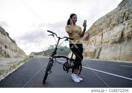 female biker using phone and earphone when biking 118672204
