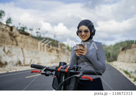 hijab woman using phone when riding bike 118672313