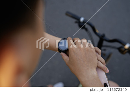male hand riding bicycle checking smartwatch 118672340
