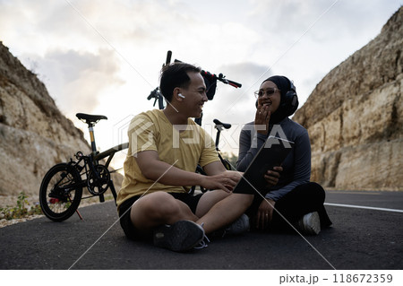 male and female biker using tablet and laughing together 118672359