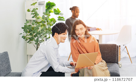 ロビーでノートパソコンを見ながら会話する多国籍の人々 118672707