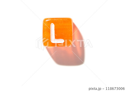 Bright orange dice with letter l on white background featuring shadow play 118673006