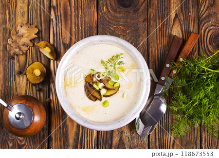 On the wooden table, there is a cream soup with fresh mushrooms as the base On the wooden table, there is a cream soup with fresh mushrooms as the base 118673553